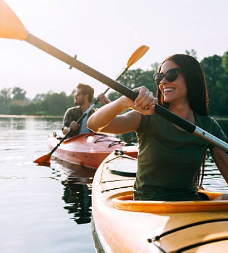 Beautiful young couple kayaking on lake together and smiling